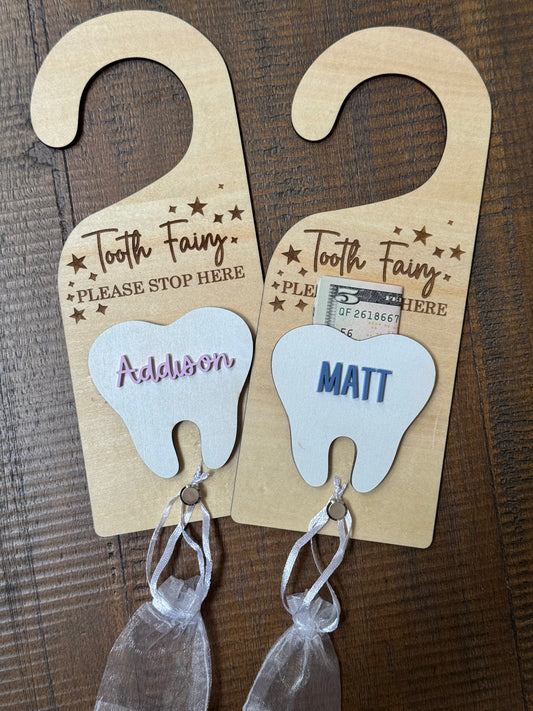 Two wooden tooth-shaped tags for the Tooth Fairy on a wooden background